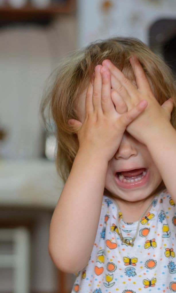 Niña llorando con las manos en la cara