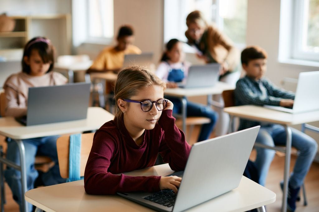 Una niña aprende electrónicamente en una computadora portátil en el aula de informática de la escuela primaria.
