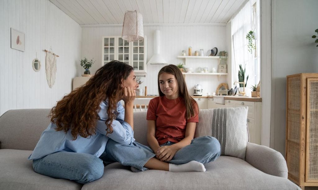 madre hablando con su hija adolescente en el sof 