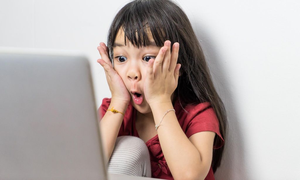 Niña sorprendida viendo la computadora