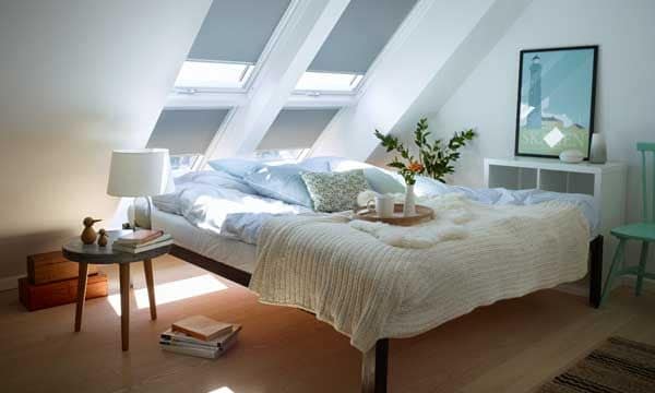 La cama, pero no cualquier cama, se convierte en uno de los escenarios preferidos e indispensables del 'hygge'. Eso sí, tiene que ser mullida, cálida, con almohadones. Ambiente con ventanas y cortinas de Velux (velux.es).
