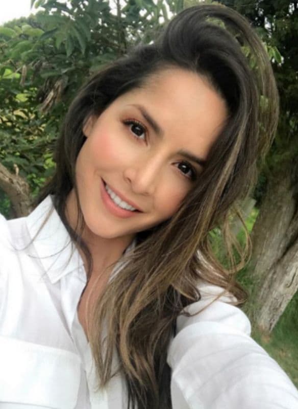 Carmen Villalobos con cabello suelto y camisa blanca, haciendo selfie 