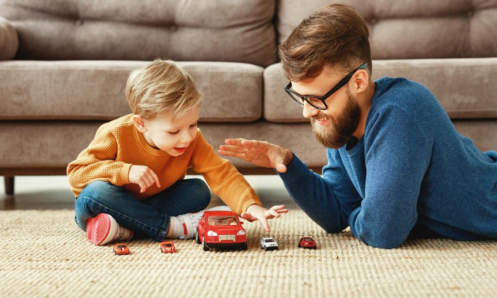 padre e hijo jugando con coches en el sal n de casa