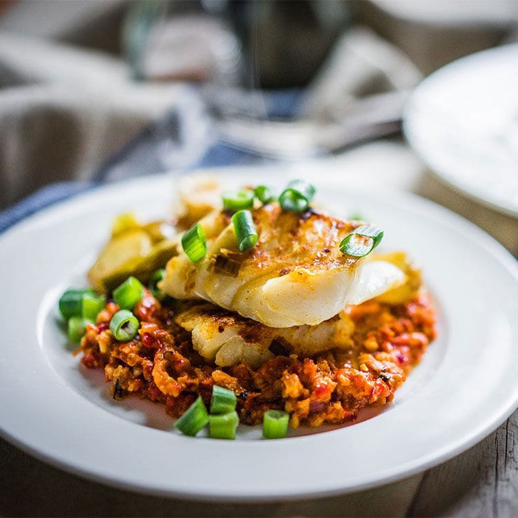 Merluza con salsa romesco y cebolla de verdeo