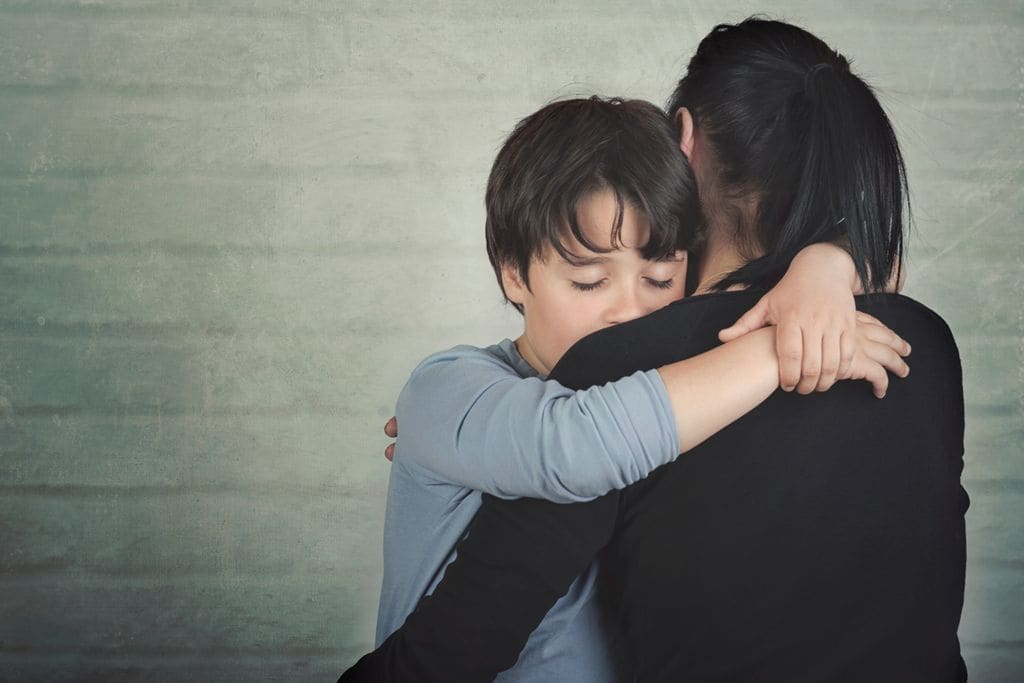 Niño triste abrazado a su madre