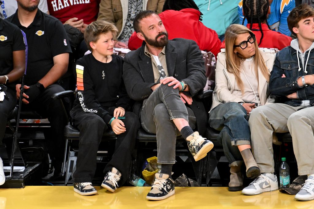 Plano medio de Ben Affleck con su hijo Samuel viendo un partido de los Angeles Lakers