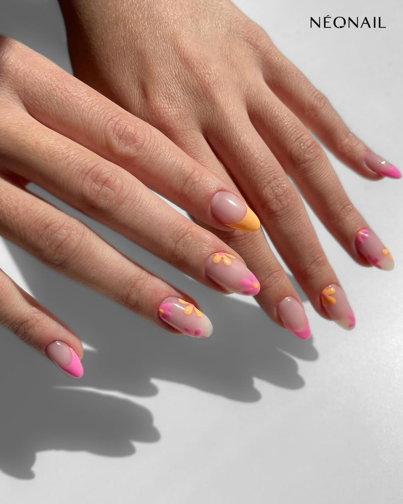 Manos de mujer con manicura francesa en rosa y naranja pastel con dibujos de flores