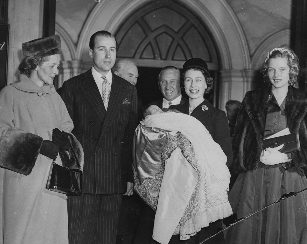 Isabel II sosteniendo al hijo de Lord Porchester después de su bautizo en St Paul's, Knightsbridge, Londres, en diciembre de 1956. En ese momento, Isabel II llevaba cuatro años en el trono. 