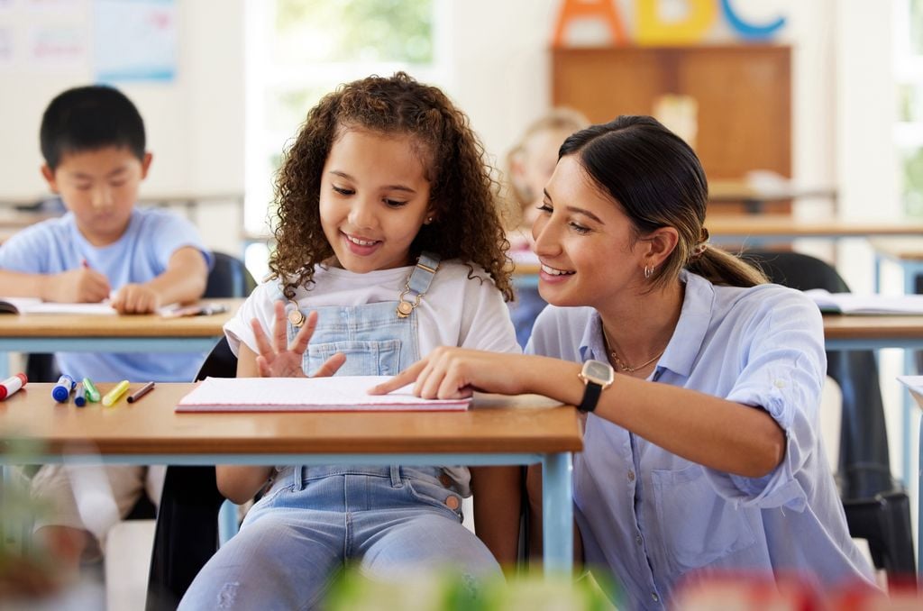 Maestra enseñando a una niña en el colegio