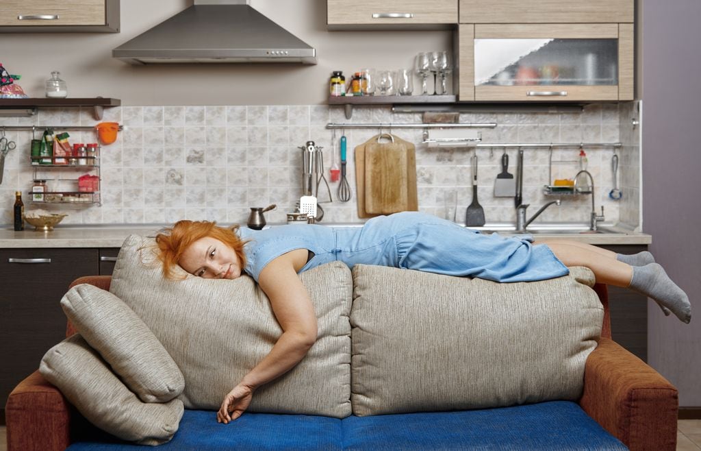 mujer pelirroja aburrida sentada sobre el borde del sofá