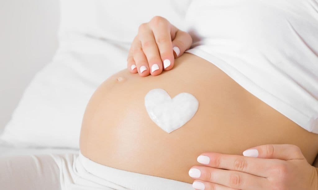 mujer embarazada con crema en la tripa en forma de coraz n