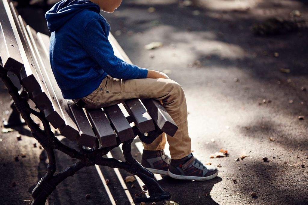 Niño triste sentado en un banco