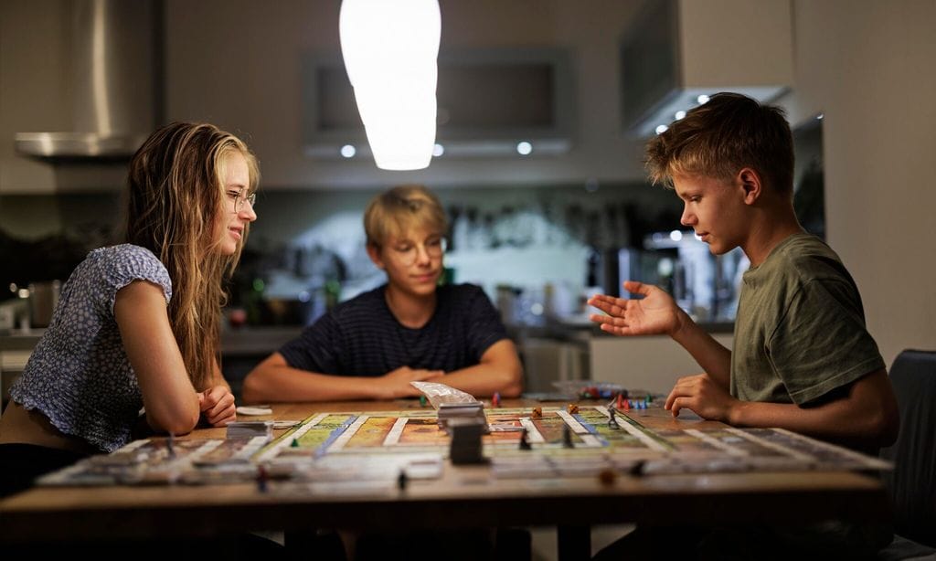 teenagers playing large board game together at home