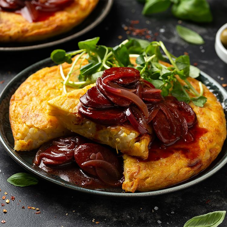 Tortilla de patata en salsa de chorizo picante y cebolla morada