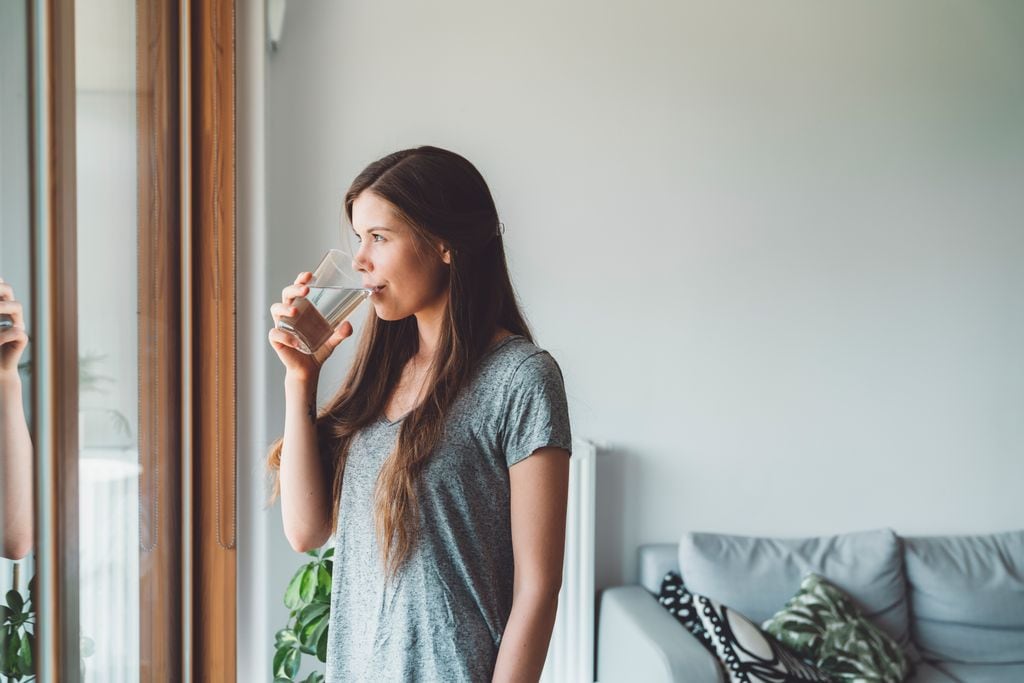 Mujer tomando un vaso de agua  con suplemento de berberina