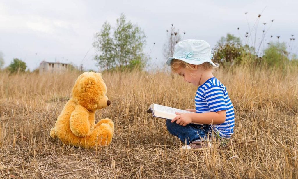 ni a leyendo con su oso peluche