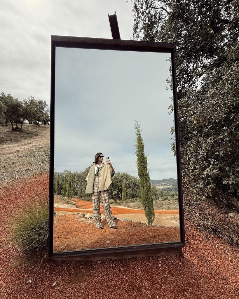 Isabelle Junot con mono de cuadros y gabardina en el campo