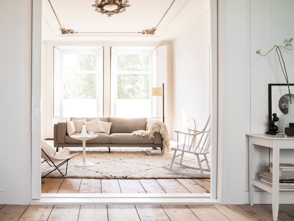 salón pintado de blanco con molduras decorativas techo y suelo de madera de lamas XL