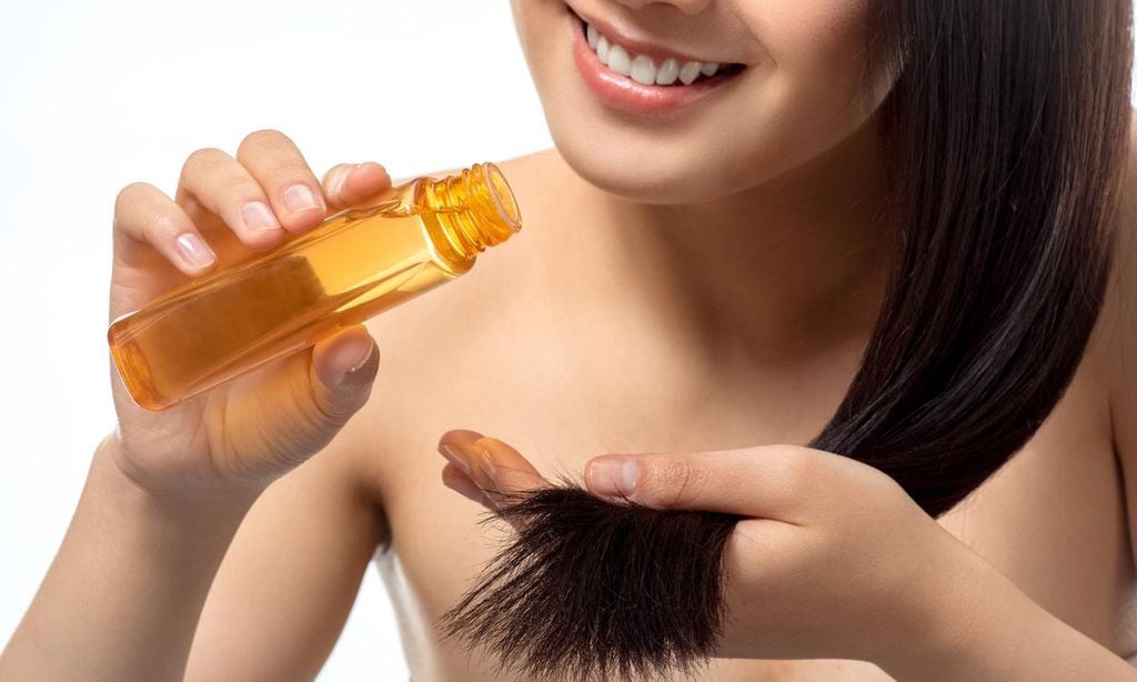 Mujer joven aplica tratamiento con aceite en el cabello