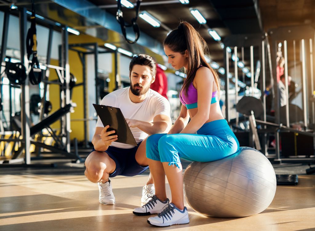 mujer con su entrenador personal en el gimnasio