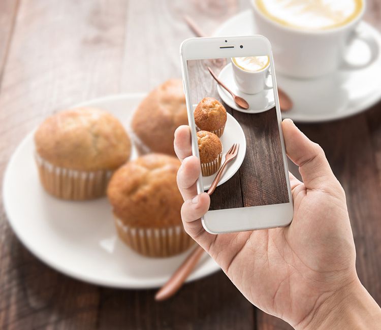 Haciendo juna foto con un móvl a unos 'muffins' terminados en un plato