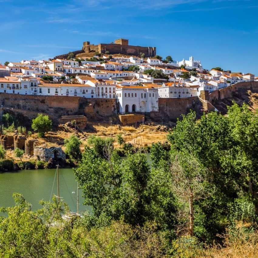 Vista de la localidad de Mértola en Portugal con el castillo sobre el caserío y junto al río Guadiana.