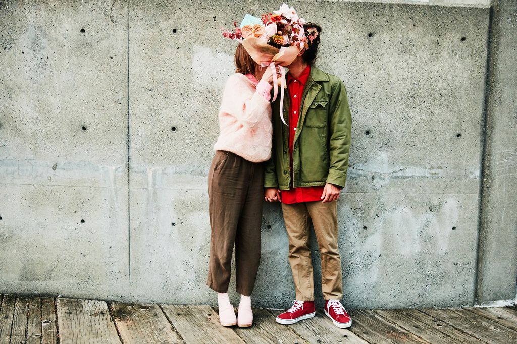 retrato de una pareja besándose detrás de un ramo de flores