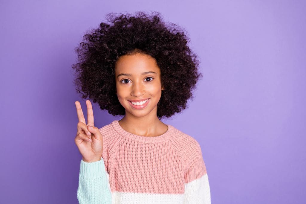 Niña sonriente con gesto de victoria en contexto de frases de paz para niños