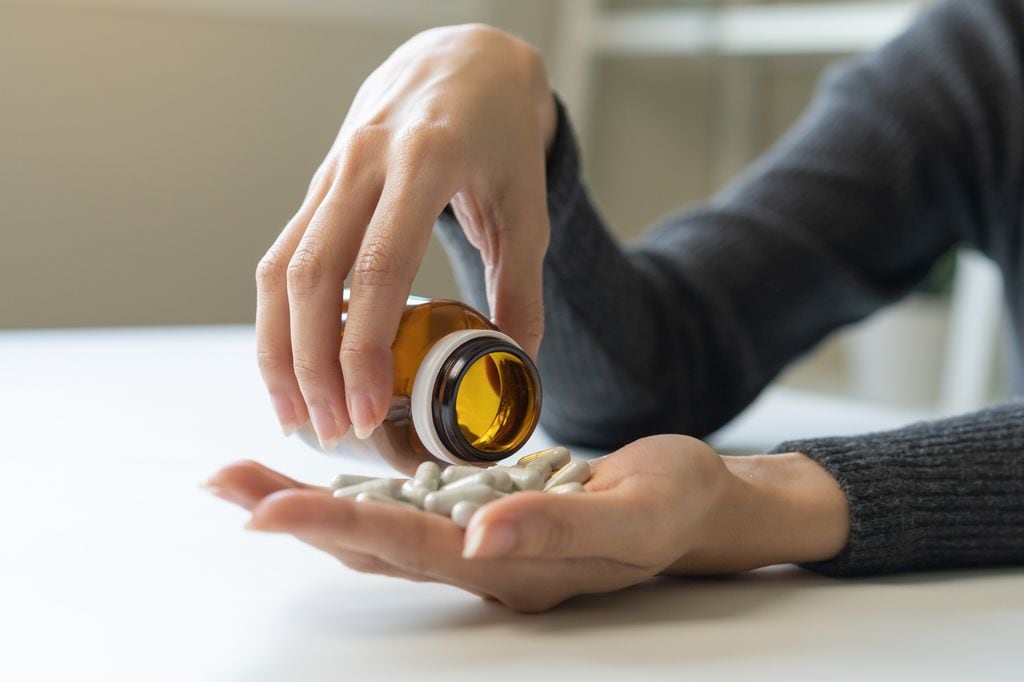 Manos de mujer con un bote de pastillas