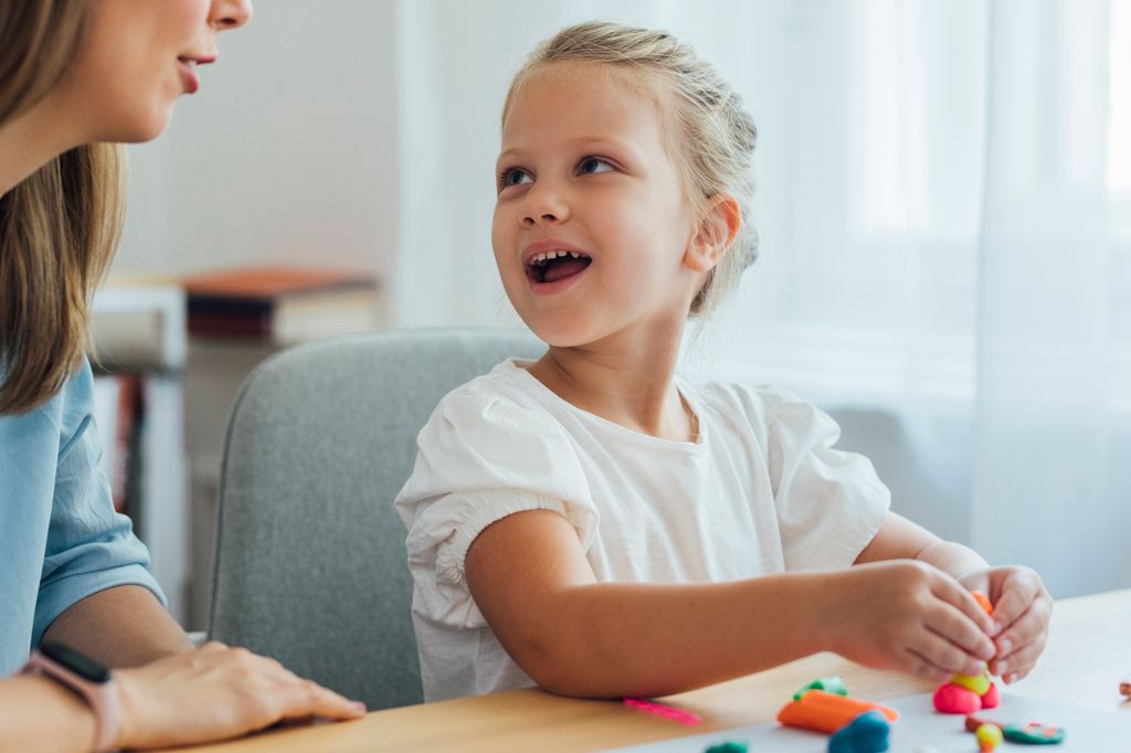 Niña habla mientras juega con plastilina