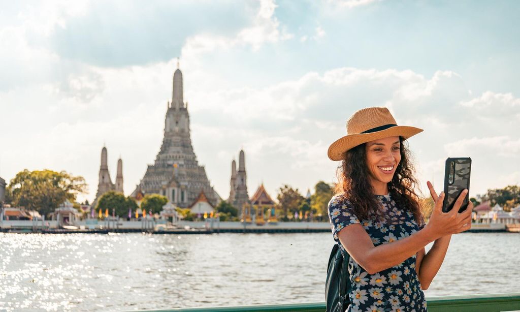 Smiling of Beautiful tourist woman traveling at Wat Arun, Bangkok on her vacation