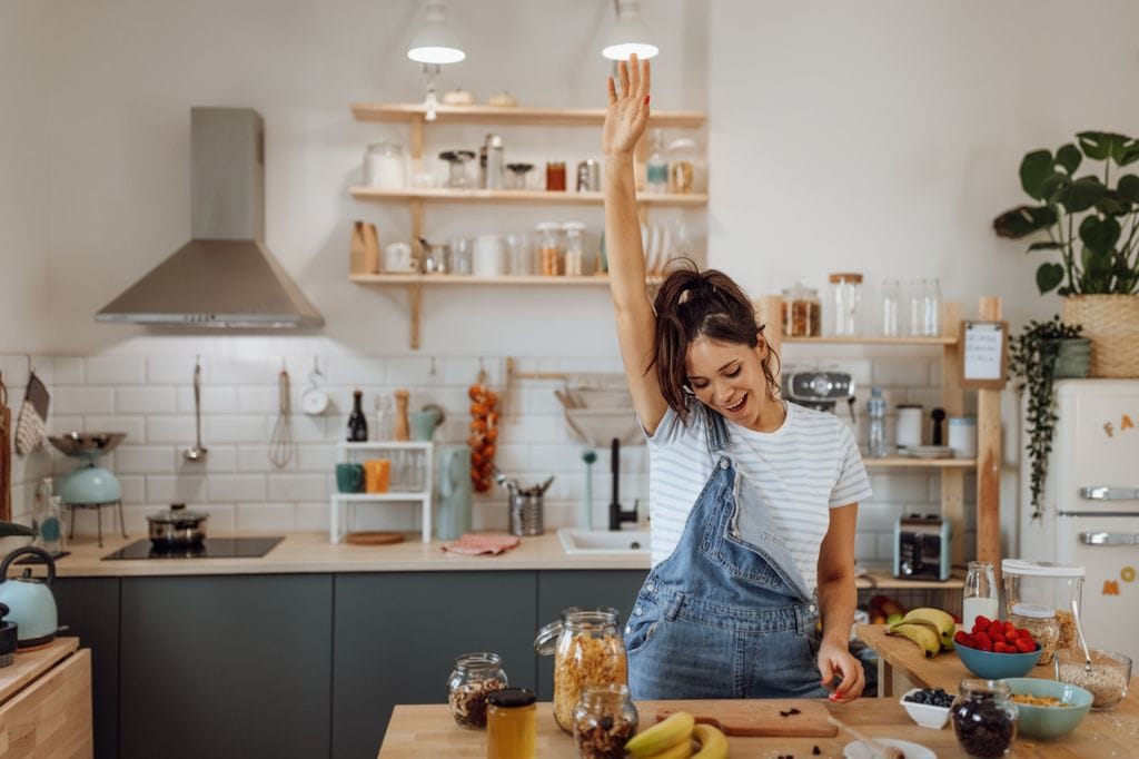 mujer alegre, bailando en la cocina mientras se prepara el desayuno