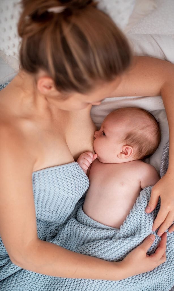 Mamá dando el pecho a su bebé en la cama