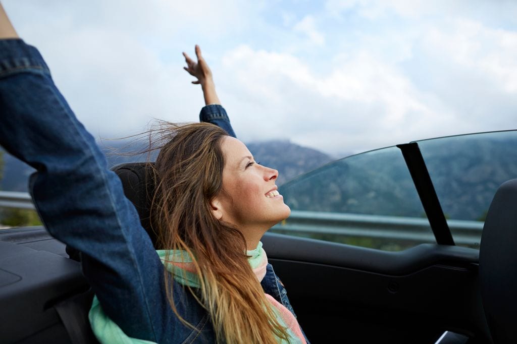 Chica sonriendo y feliz en un coche