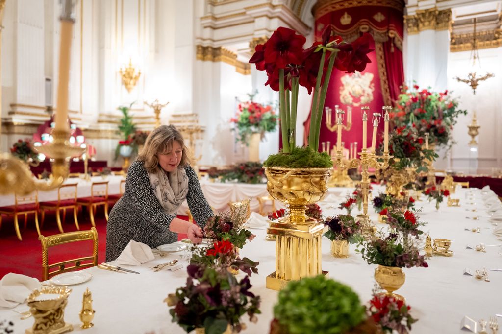 Una florista real aplica los toques finales a las flores de temporada en las mesas del salón de baile del Palacio de Buckingham, Londres, antes del Banquete Estatal para el Emir de Qatar y su esposa en el Palacio de Buckingham en Londres