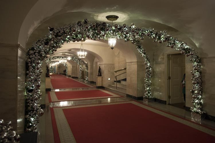 Arcos de bolas y campanas de Navidad decoran uno de los pasillos principales de la casa: es como pasar debajo de un pasillo de ramas y hojas artificiales
