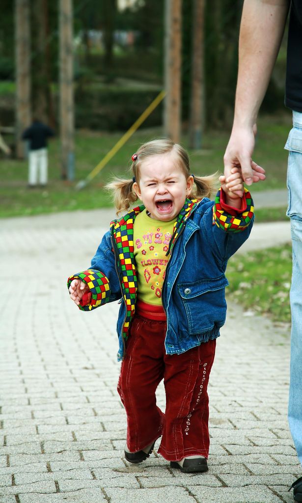 Niña con rabieta de la mano de su padre