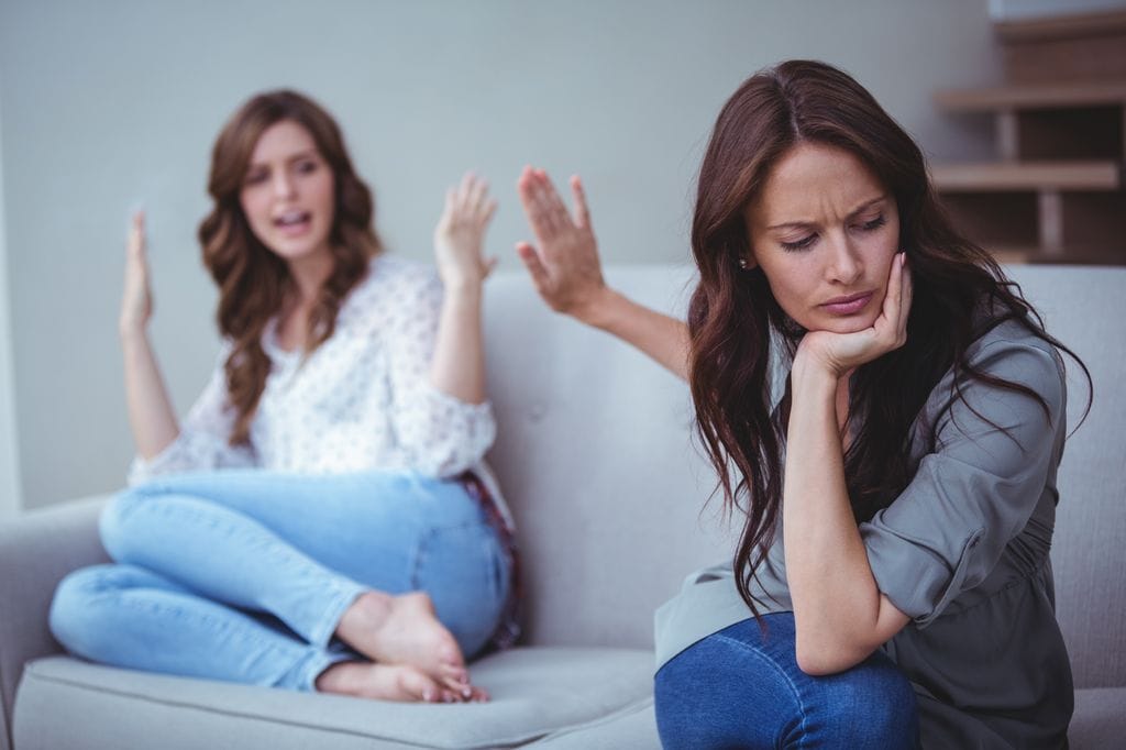 dos amigas discutiendo en el sofá