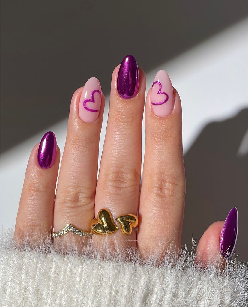 Mano con manicura cromada en rosa y dibujos de corazones