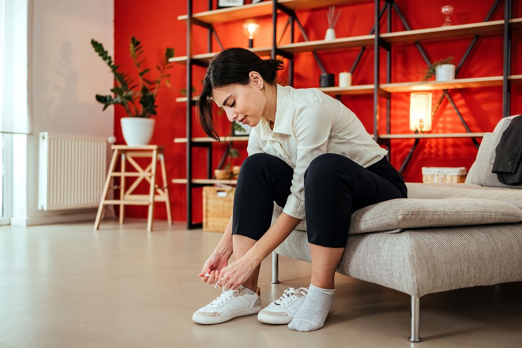 mujer sentada en un sillón poniéndose unas zapatillas de deporte