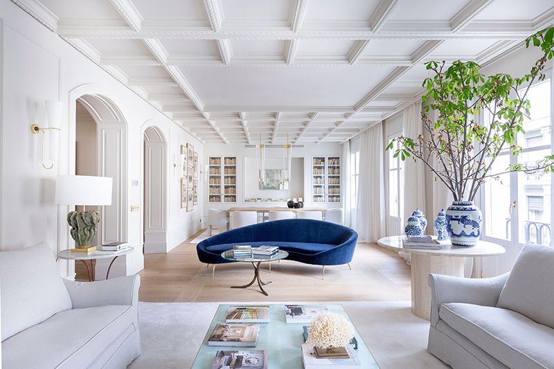 Salón en blanco con un sofá de forma orgánica en tono azul que marca un contraste de color