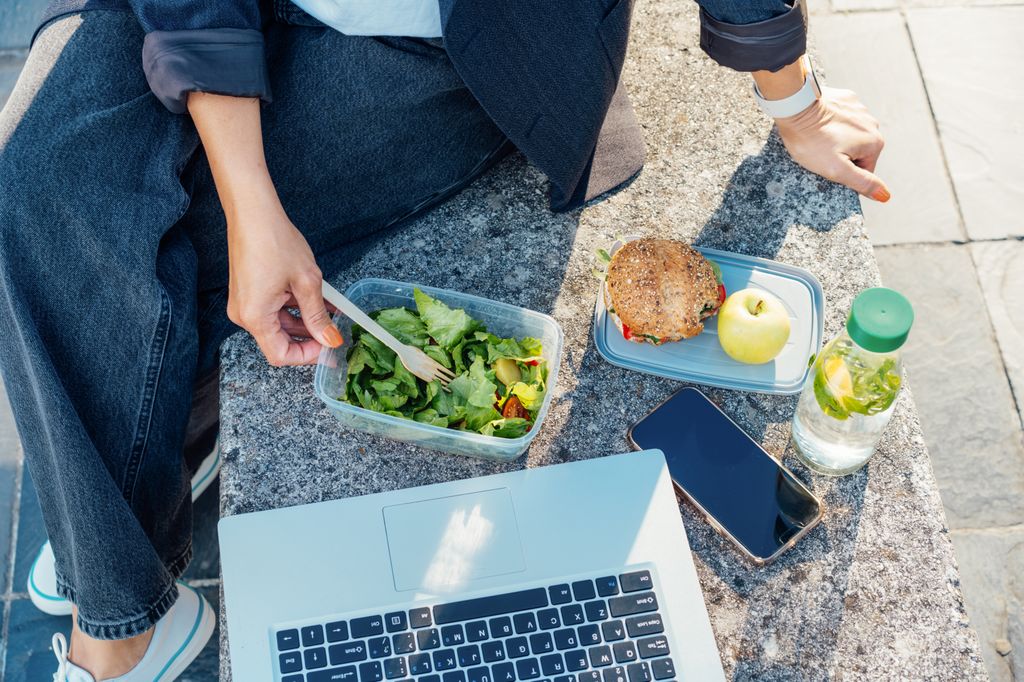 woman eating in front of laptop