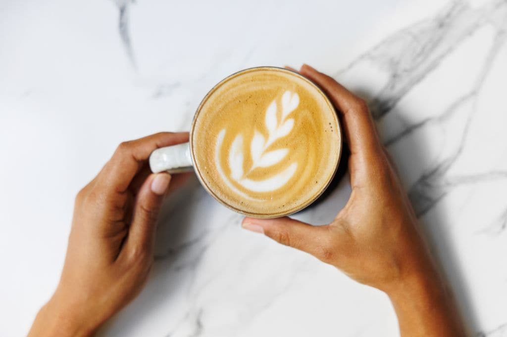 Mujer sujetando una taza de café recién hecho en un plano desde arriba