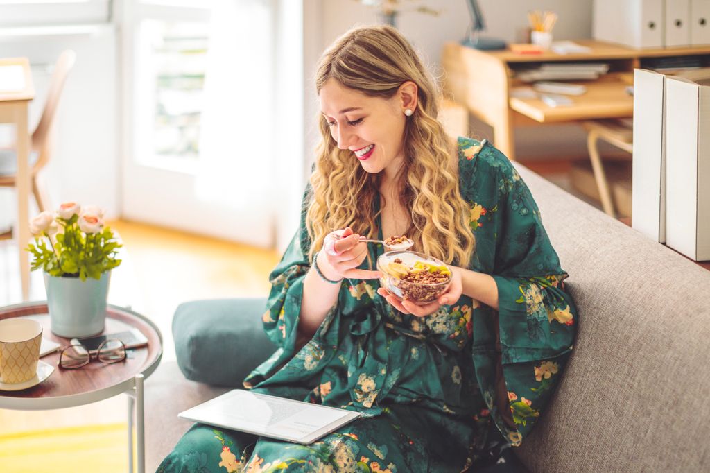 mujer desayunando en el sofá de casa