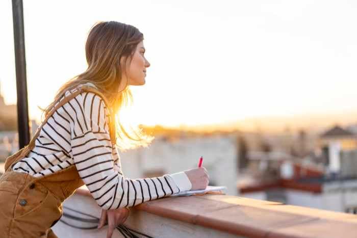 mujer escribiendo mirando al horizonte