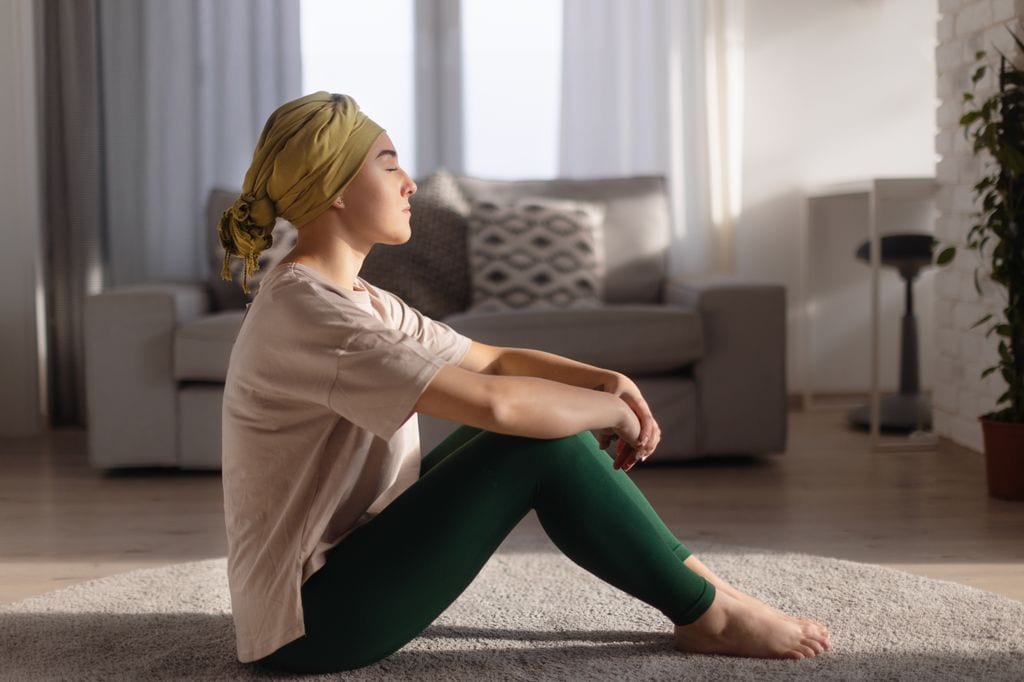 mujer con cáncer meditando en el suelo