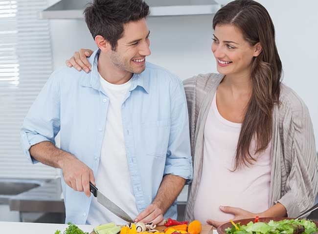 pareja embarazada preparando comida