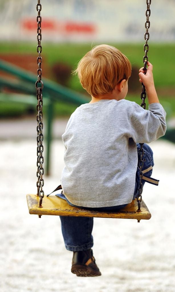 Niño triste sentado en un columpio