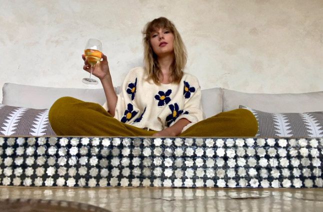 Taylor con una copa de vino sentada en un sofá