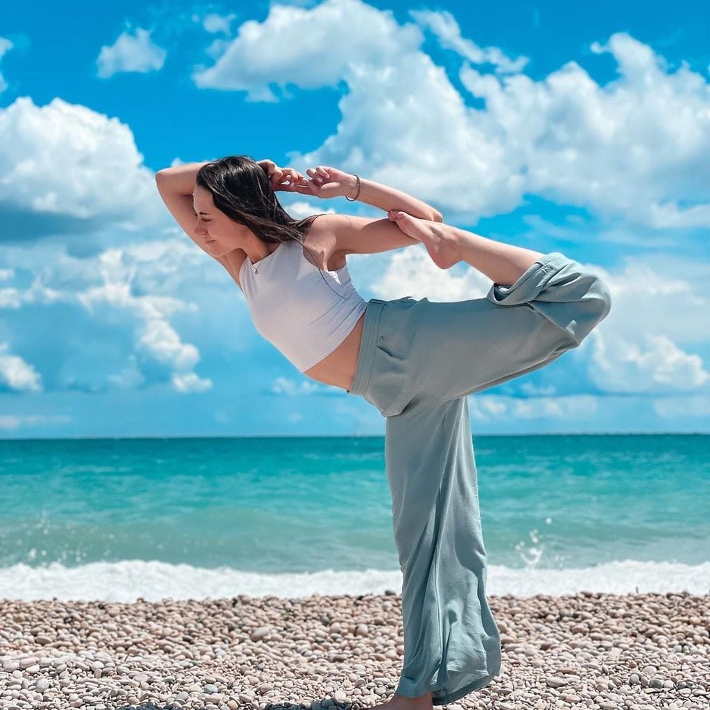 mujer joven haciendo yoga junto a la playa